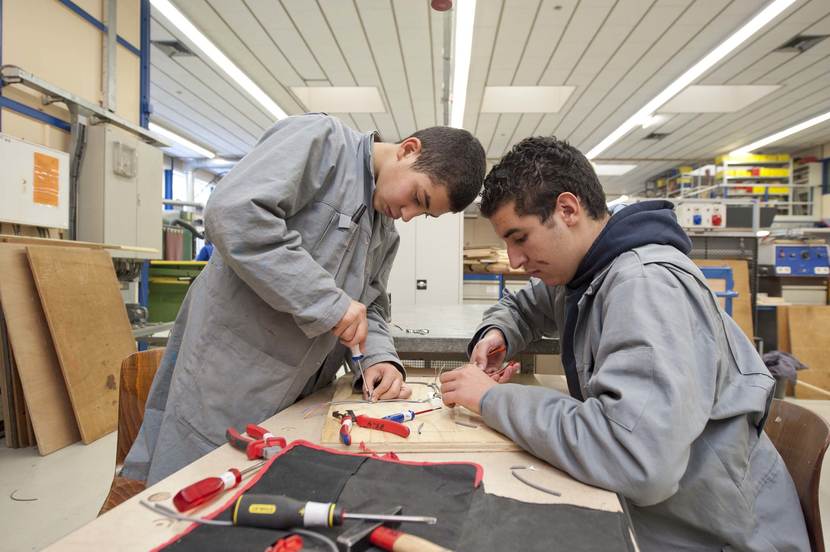 2 scholieren aan de werktafel met gereedschap in de weer