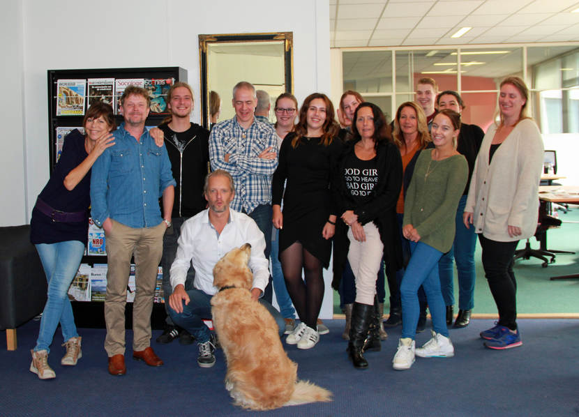 Een groep collega's met een hond in het midden